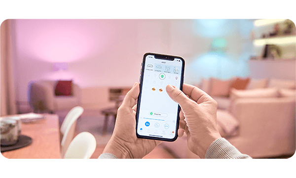 En hånd som holder en mobil med farvet belysning I baggrunden