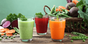 ulike typer juice på et bord med grønnsaker