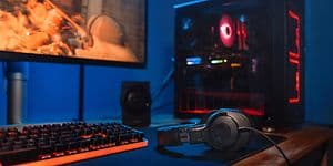 Gaming PC-opsætning med skærm, desktop tower, tastatur og hovedtelefoner, der ligger på bordet