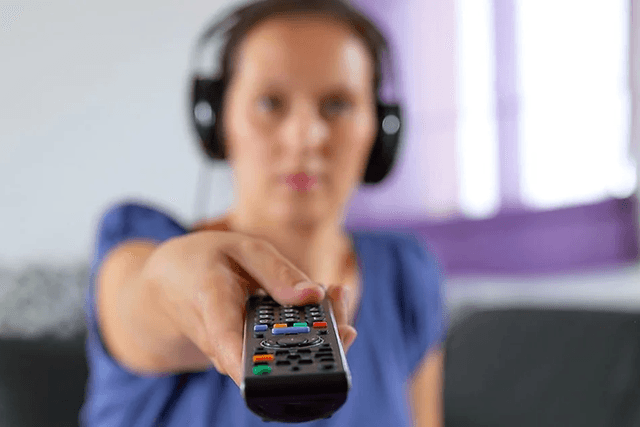 Kvinde med headset peger mod TV med fjernbetjening