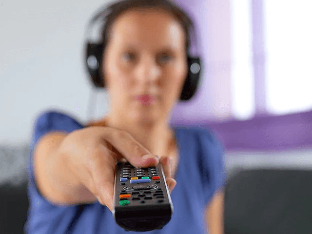 Kvinde med headset peger mod TV med fjernbetjening
