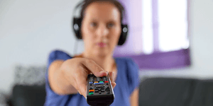 Kvinde med headset peger mod TV med fjernbetjening
