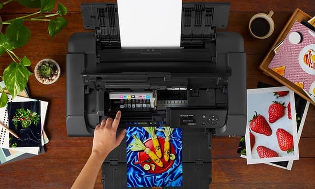 Canon Pixma printer på et bord med flere ferdigutskrevne bilder rundt