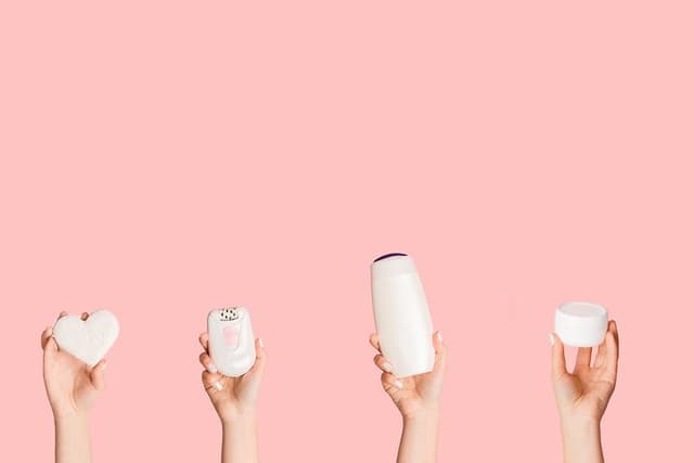 Hænder, der holder forskellige hårfjerningsprodukter som epilator, barbermaskine og ipl