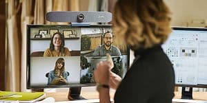 Kvinna med ryggen till ser på en skärm med fyra andra personer som deltar i ett videomöte. 