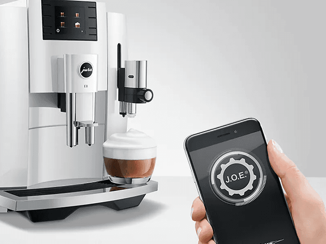 Jura kaffemaskin og en person som holder en smarttelefon