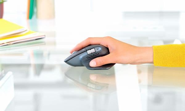 person holder en Logitech datamus på et ryddig skrivebord