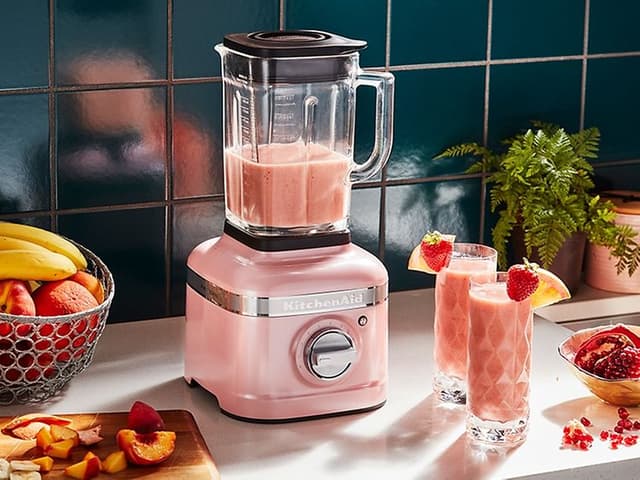 rosa KitchenAid-blender på kjøkkenbenk med frukt og smoothier