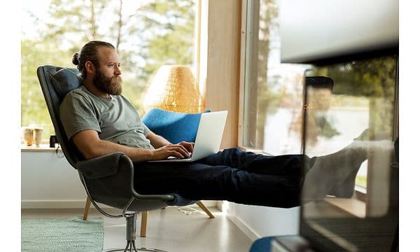 Mand sidderr på en stol med bærbar computer