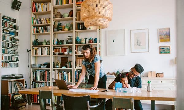 Kvinna som arbetar på en laptop och en man med ett barn bredvid henne