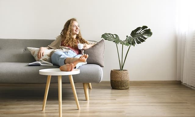 Kvinne sitter i sofa med en kaffekopp