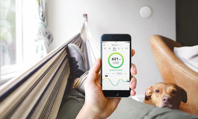 Person holder smarttelefon med airthings app på skjermen