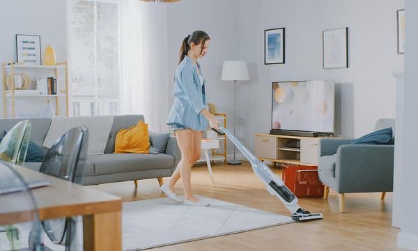 Kvinna som dammsuger golvet med en sladdlös dammsugare