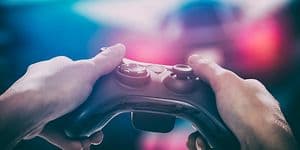 Kädet pitelevät peliohjainta televisionäytön edessä