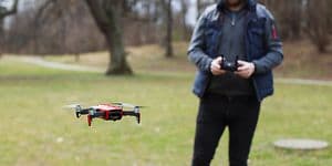 Mann som flyr drone utendørs mellom noen trær