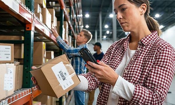 Kvinde, der scanner en pakke med sin telefon