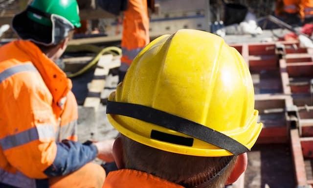 Rakennustyömiehet työmaalla kypärät ja kuulosuojaimet päässään