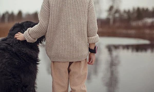 Lapsi Xplora X5 -älykello yllään silittää koiraa