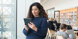 Kvinne som står i bibliotek med nettbrett