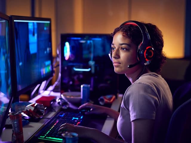 Kvinne med gaming-headset som sitter foran en stasjonær gaming-PC