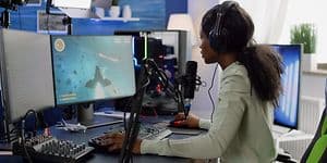 Jente som sitter foran sin stasjonære gaming-PC og strømmer