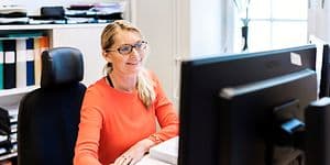 Kvinna som sitter framför en datorskärm på ett kontor
