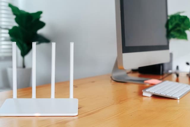 Moderne Wi-Fi-router på et lyst bord på hjemmekontoret