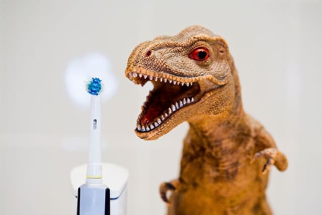 Elektrisk tannbørste ved siden av en lekedinosaur