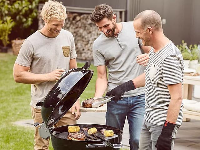 Kolme hymyilevää miestä seisovat pallogrillin ympärillä