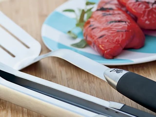 Weber-grillilasta ja -grillipihdit grillin sivupöydässä grillattujen tomaattien vieressä