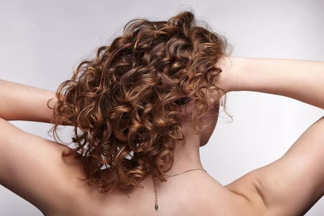 En dame står med ryggen til og holder hendene i håret