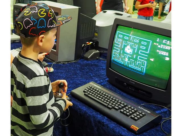 En dreng spiller pac man på et gammelt CRT TV