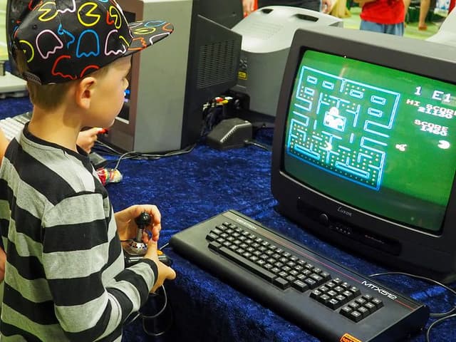 En gutt spiller Pacman på en gammel TV-skjerm