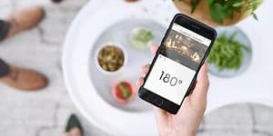 En hånd, der holder en smartphone med en app, der viser kameraet i en smart ovn