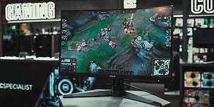 En ASUS gaming-skjerm foran PCSPECIALIST-logoen i en Elkjøp-butikk.