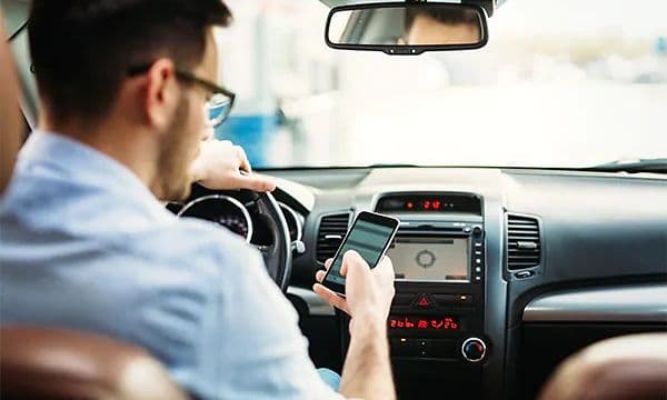 Mann i bil som ser på smarttelefon