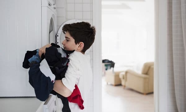 En gutt som tar tøy ut av vaskemaskinen
