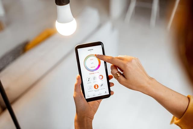 Kvinde der styrer hendes lys fra en mobiltelefon