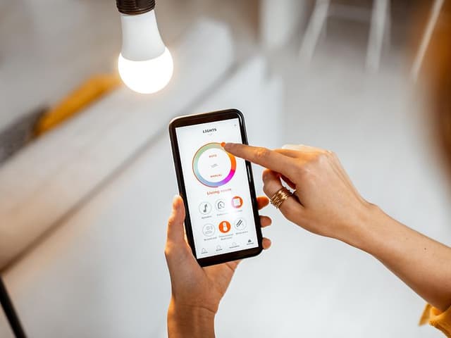 Kvinde der styrer hendes lys fra en mobiltelefon