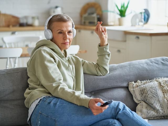 Kvinne med hodetelefoner ser TV