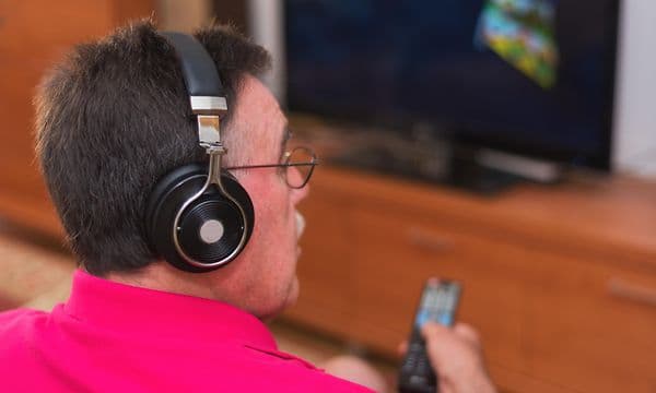 Mann med hodetelefoner ser TV