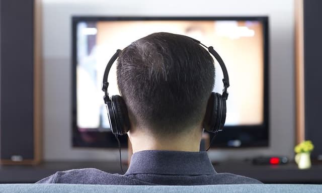 Mann med hodetelefoner ser TV