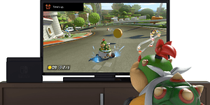 Nintendo switch med bild på ett monster som sitter framför en skärm som visar ett TV-spel.  