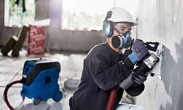 Construction worker vacuuming concrete dust with Nilfisk Attix 44-2M IC