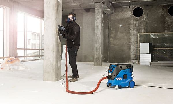 Construction worker polishing concrete wall and using Nilfisk Attix vacuum