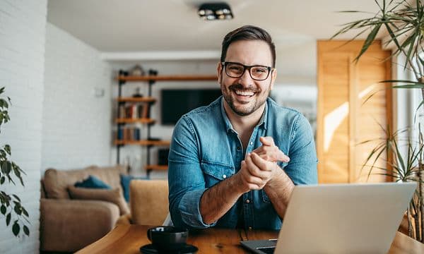 Smilende mand sidder ved sin bærbar computer