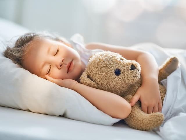 Jente sover med teddybjørnen sin