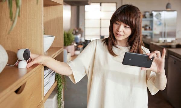Kvinde med smartphone ser på nest-kamera