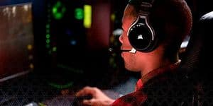 Man som sitter framför en dator och har på sig ett svart gaming-headset från Corsair.