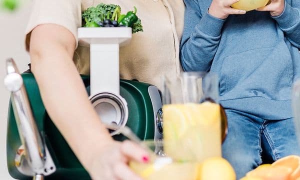 En kvinde laver juice og en dreng drikker juicen